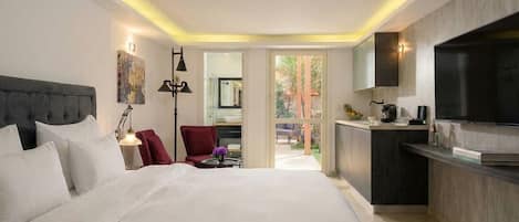 A modern hotel room with a large bed, a desk, a chair, a TV, and a view of the outdoors.