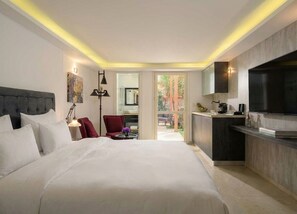 A modern hotel room with a large bed, a desk, a chair, a TV, and a view of the outdoors. - Carmella Spa & Boutique Hotel (Haifa)