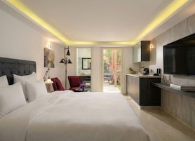Habitación de hotel moderna con una cama grande, un escritorio, una silla, un televisor y vistas al exterior.