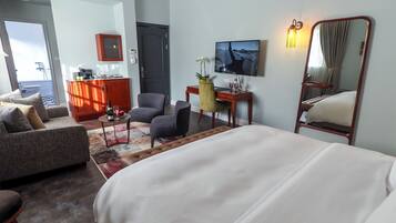 A hotel room with a bed, a sofa, a desk, a chair, and a view of the outdoors.