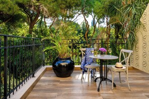 A balcony with a wooden floor, metal railing, a round table with chairs, a vase with flowers, and a potted plant. - Carmella Spa & Boutique Hotel (Haifa)