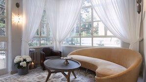 Habitación de esquina con un sofá color beige, una mesa redonda y una planta en maceta.