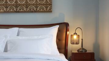 A neatly made bed with white linens, a wooden headboard, and a bedside table with a lamp.