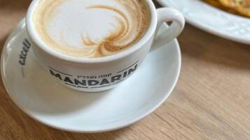 Une tasse de café décorée avec un motif en latte, une assiette avec une part de gâteau et un bol de salade.