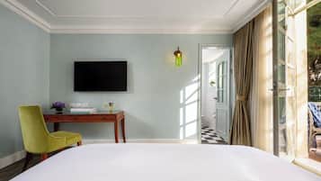 Habitación de hotel con una cama grande, un escritorio con una silla, un televisor de pantalla plana y vistas al exterior.