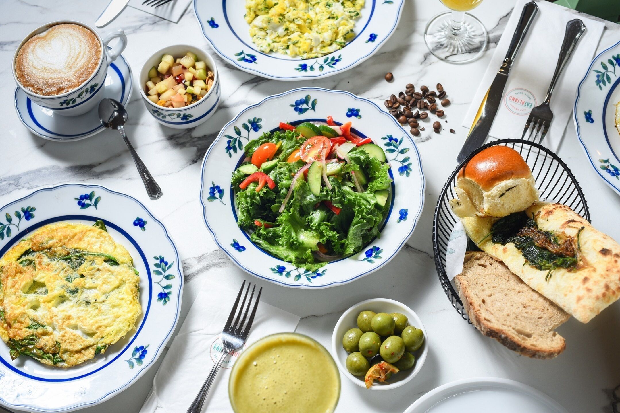 A table with various dishes including a salad, bread, and a cup of coffee.