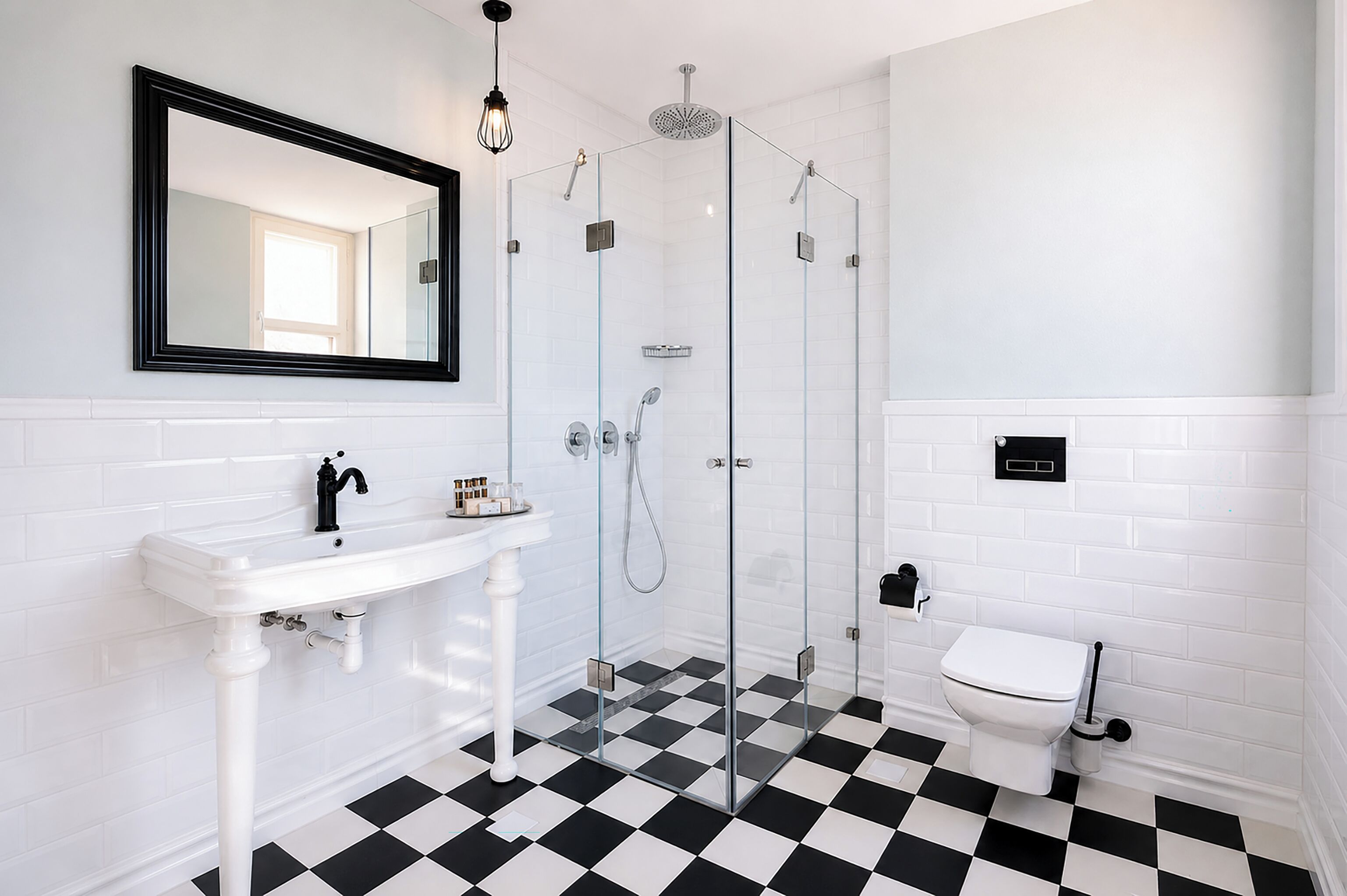 A bathroom with a white sink, a mirror, a glass-enclosed shower, and a toilet.