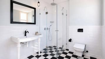A bathroom with a white sink, a mirror, a glass-enclosed shower, and a toilet.
