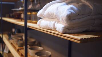 A shelf with neatly folded white towels and a few bowls on a wooden shelf.
