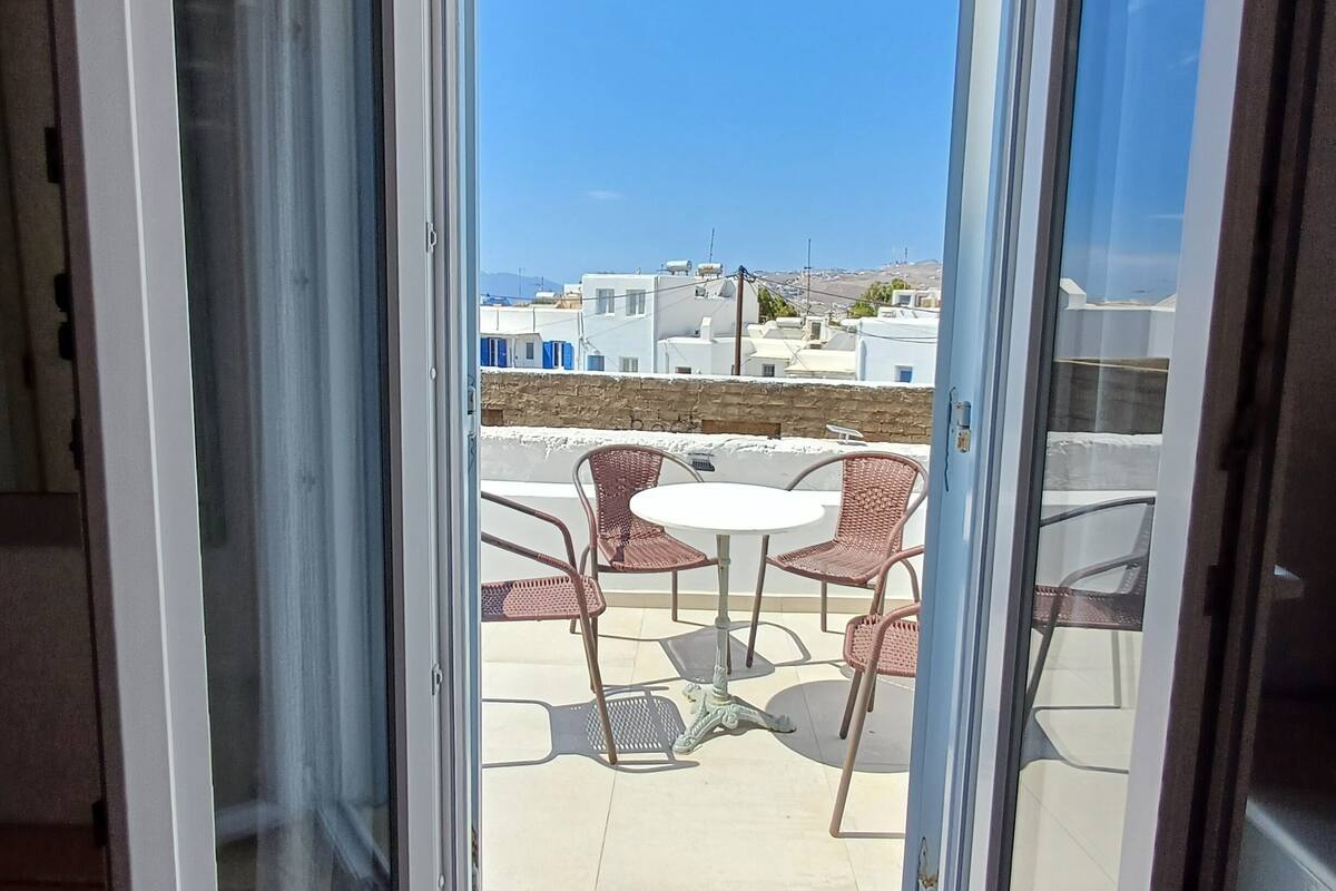 A balcony with a clear view of the surrounding buildings and a table with chairs.
