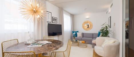 Una sala de estar moderna con una mesa de comedor redonda, un sofá y un televisor.
