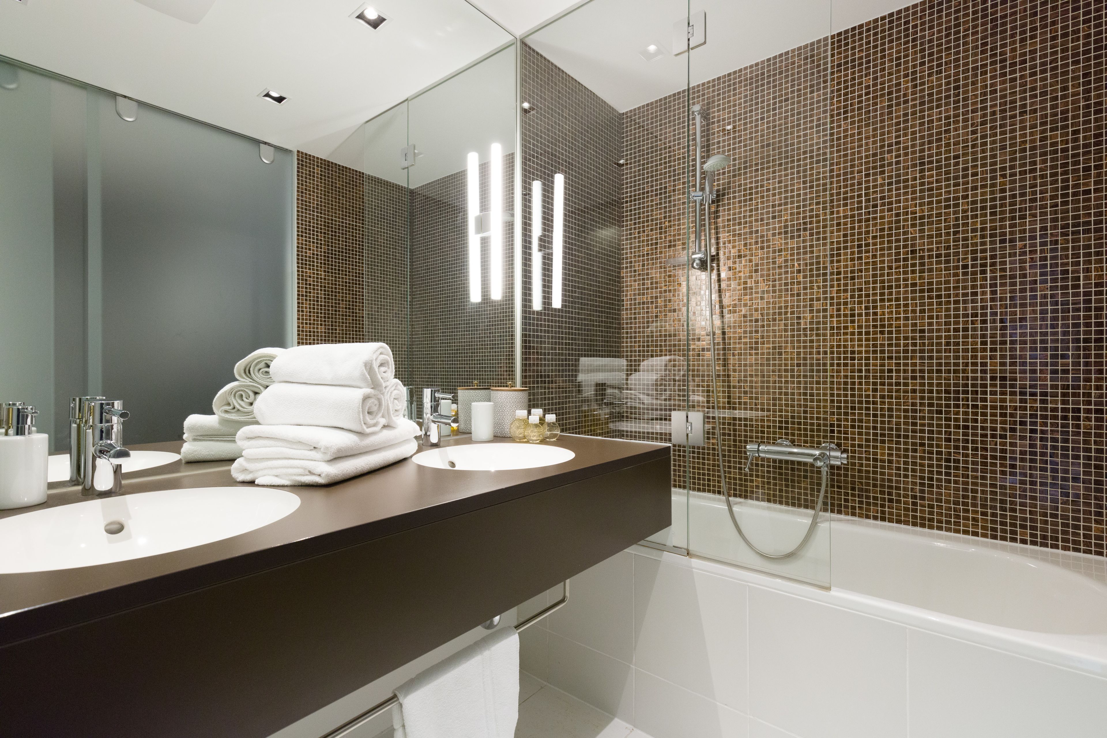 A modern bathroom with two sinks, a large mirror, and a shower.
