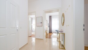 A spacious hallway with a modern design, featuring a large mirror, a console table with a lamp, and a door leading to another room. - Rafael Kaiser - Premium Apartments City Centre  (Vienna)