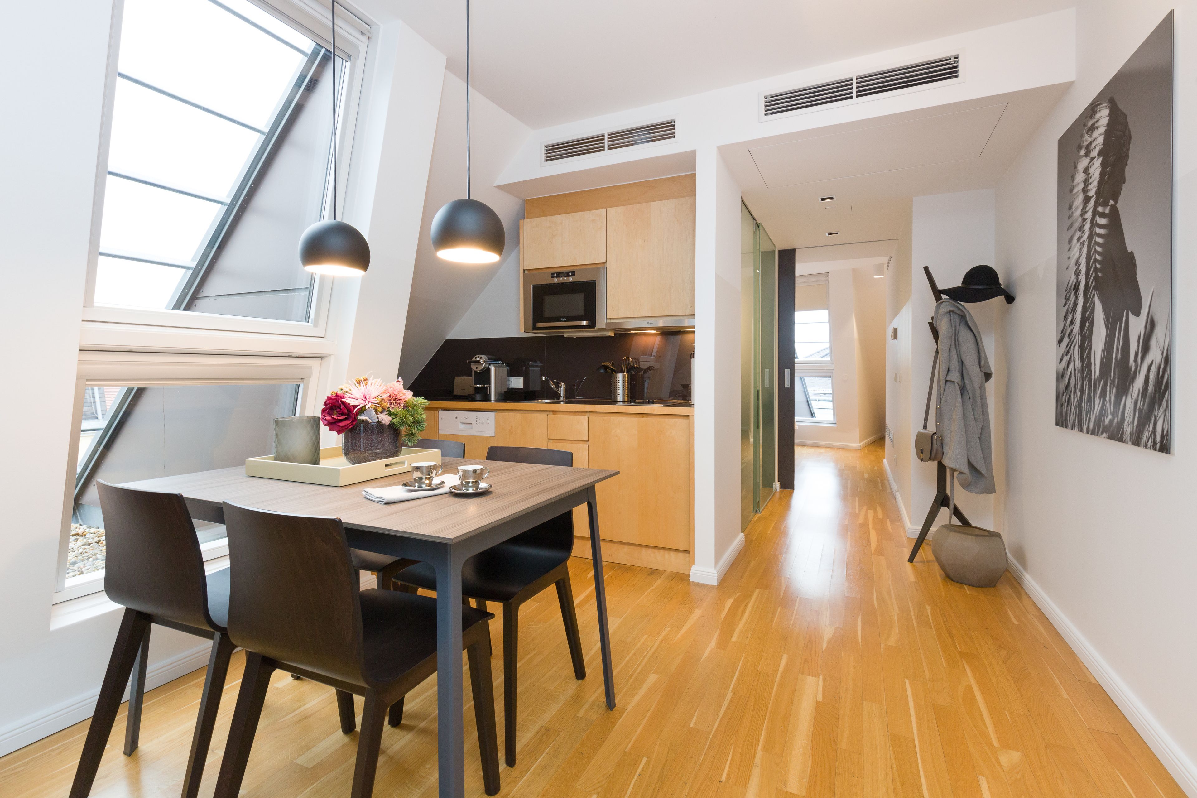 A modern kitchen with wooden cabinets, a microwave, and a dining area with a table and chairs.