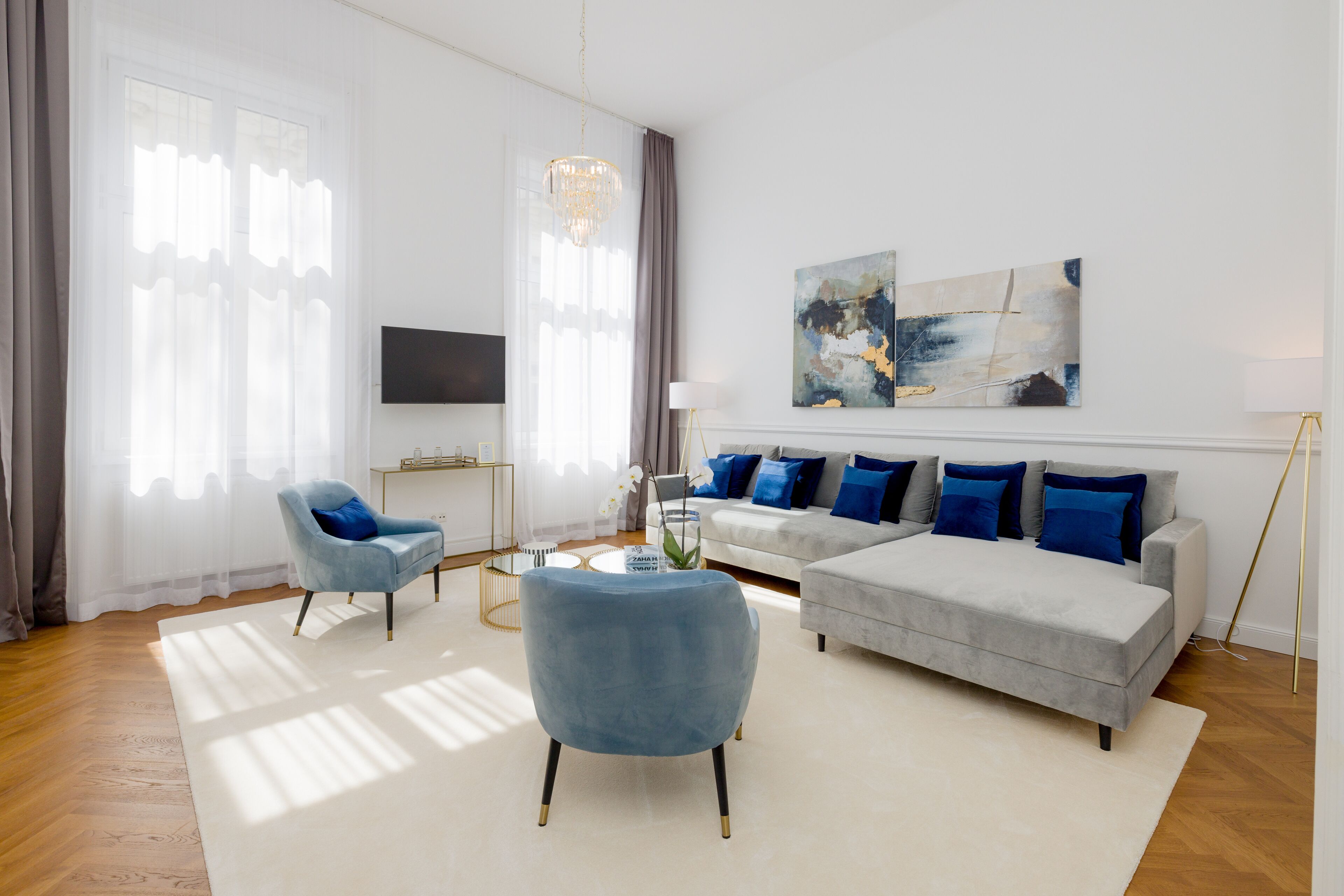 A modern living room with a grey sofa, blue armchairs, and a coffee table.