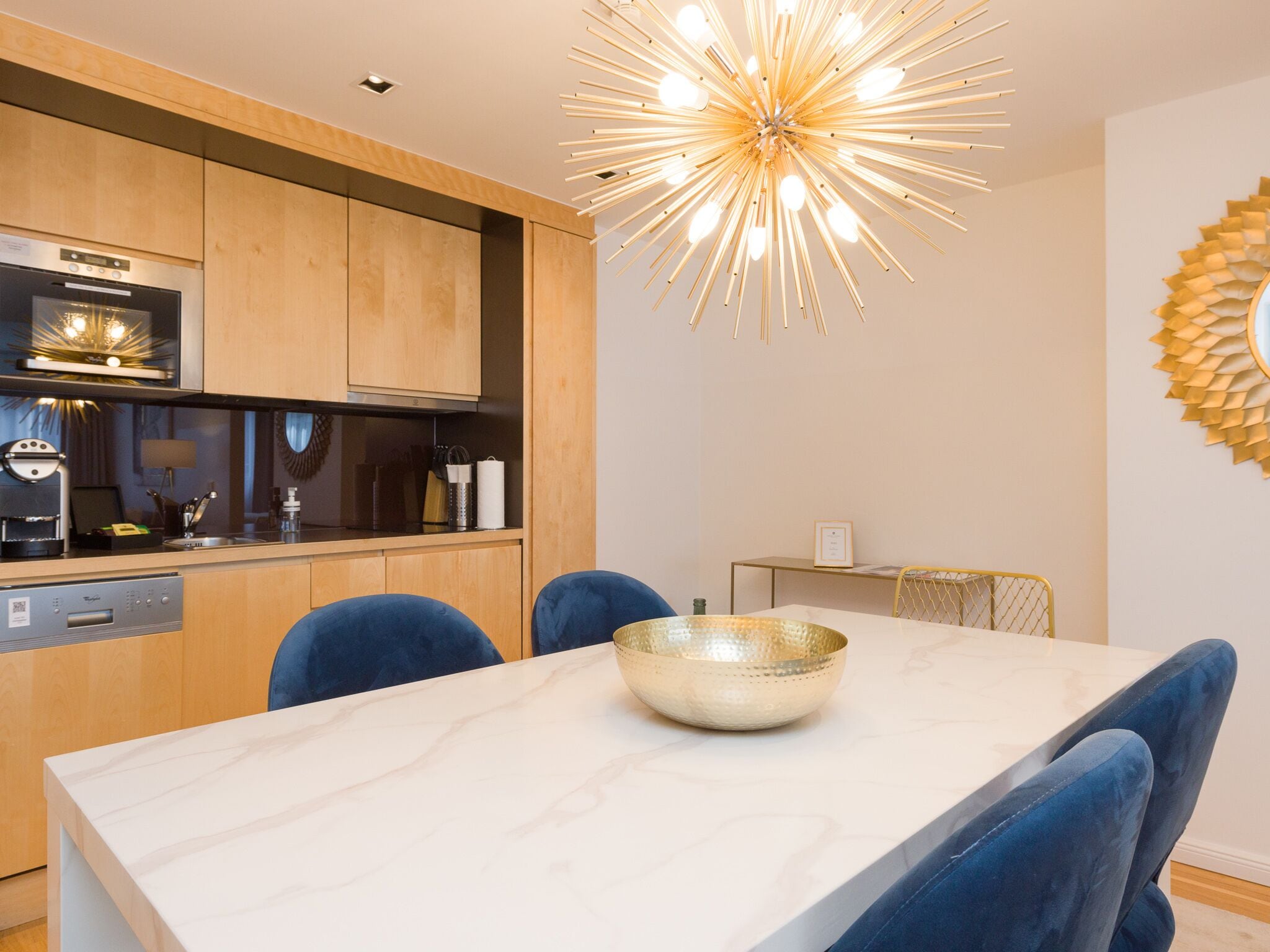 A modern kitchen with wooden cabinets, a built-in oven, and a unique ceiling light fixture.