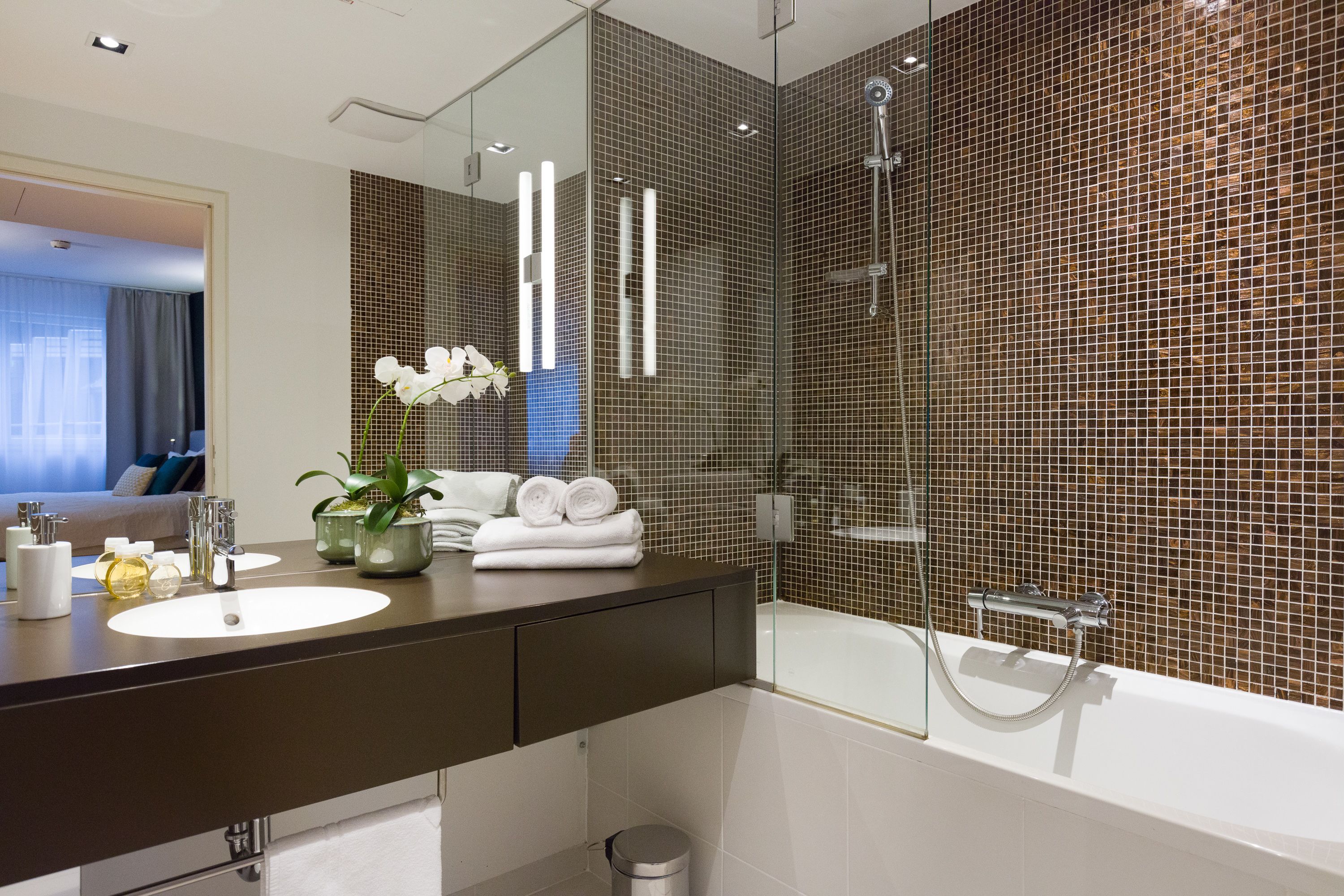 A modern bathroom with a large mirror, a sink, a bathtub, and a shower.