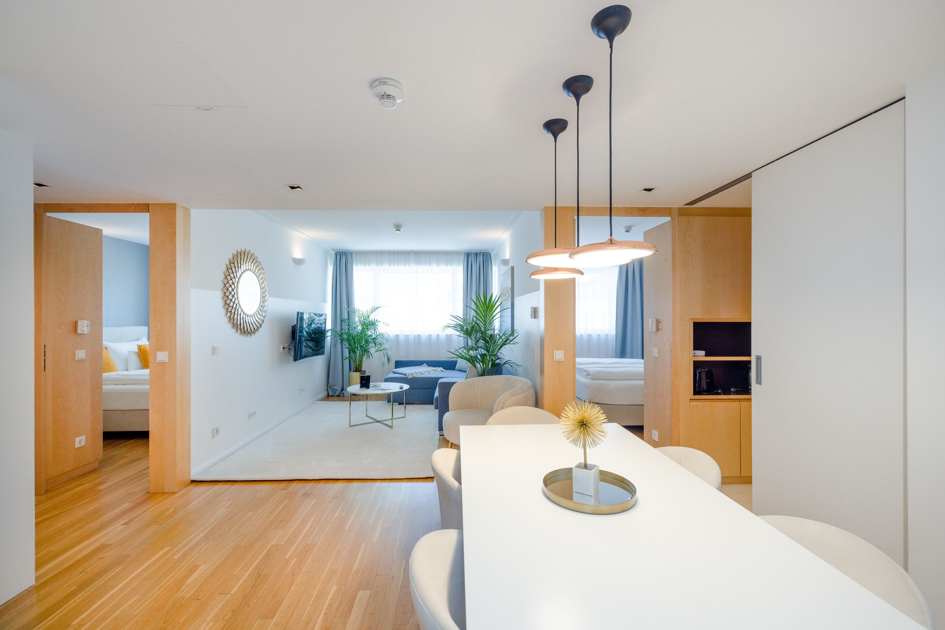 Una sala de estar moderna con comedor, suelo de madera y un amplio ventanal con cortinas.