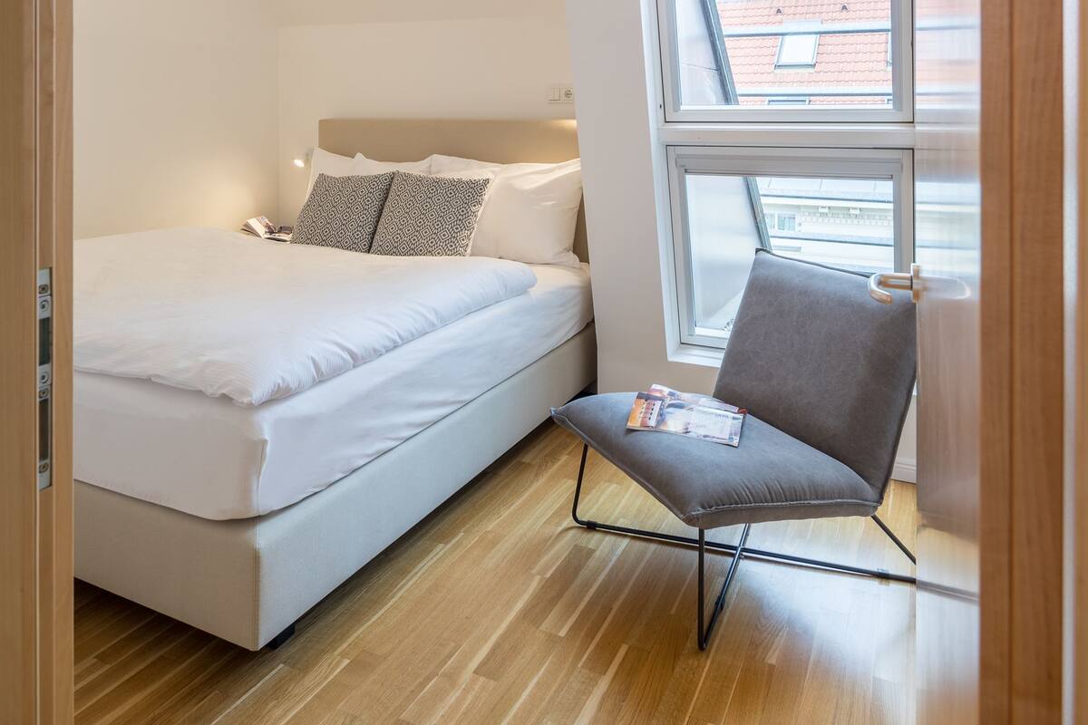 Una camera da letto moderna con un letto, una sedia e una finestra.