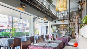 A restaurant with multiple tables, a staircase, and a view of the street outside. - The Beach Cha Am Residence (Cha-am)