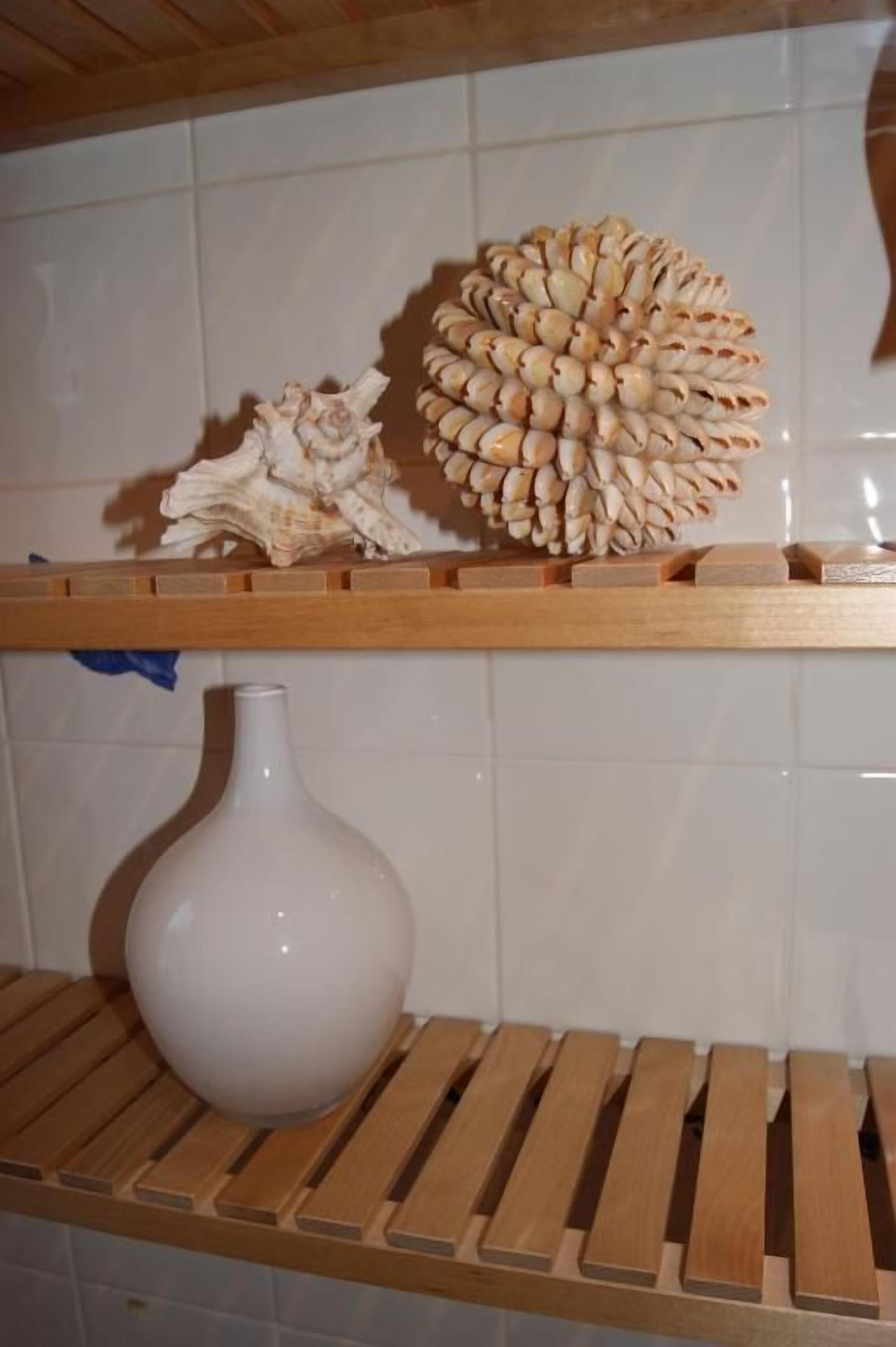 Une étagère de cuisine avec un vase blanc et un coquillage décoratif.
