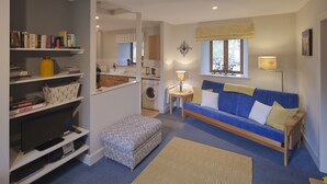 Un espacio habitable pequeño con un sofá, un reposapiés y una estantería.