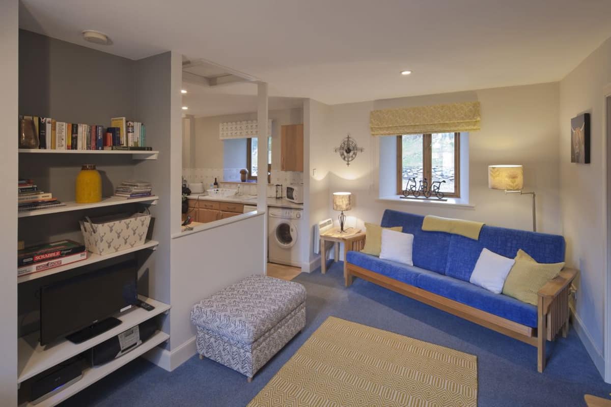 A compact living space with a sofa, ottoman, and a bookshelf.