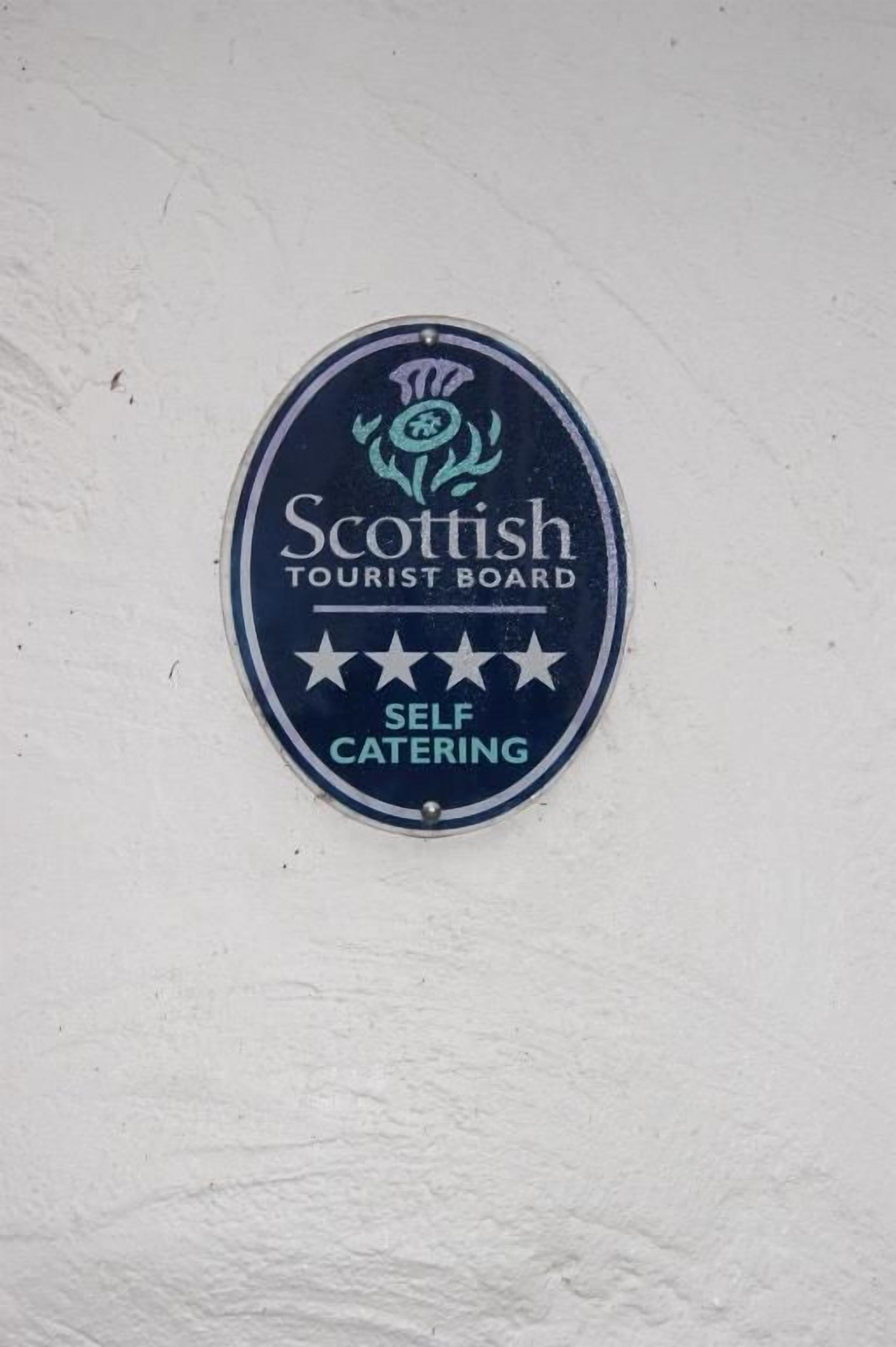 En plakett på en vägg med texten: ”Scottish Tourist Board – boende med självhushåll.”