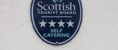 En plakett på en vägg med texten: ”Scottish Tourist Board – boende med självhushåll.”