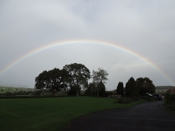 A rural landscape with a rainbow arching over a road. - Cedar House (Minehead)