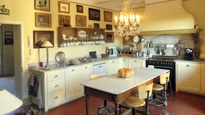 A kitchen with a central island, a chandelier, and various kitchen appliances.