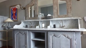 A bathroom with a marble sink, a large mirror, and a cabinet with shelves.