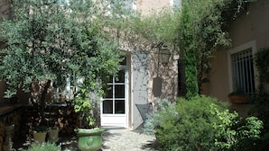 A courtyard with a door, potted plants, and a stone wall.