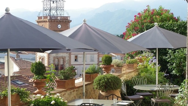 An outdoor patio with tables and chairs, surrounded by potted plants and flowers.