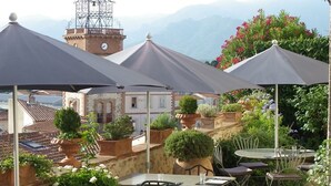 An outdoor patio with tables and chairs, surrounded by potted plants and flowers. - Château D'ortaffa (Ortaffa)