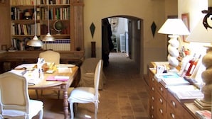 A cozy room with a wooden bookshelf, a dining table with chairs, and a desk with a lamp.