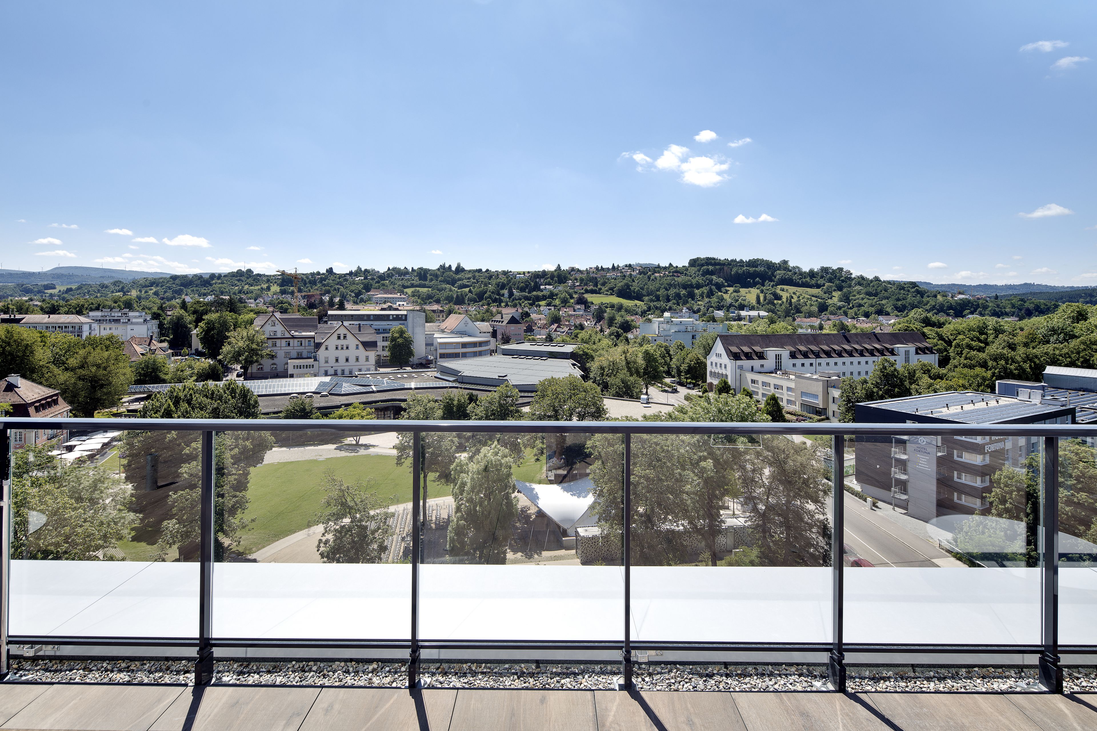 A high-rise building with a large glass balcony overlooking a town.
