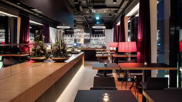 A modern bar area with wooden counters, seating, and a well-lit interior.