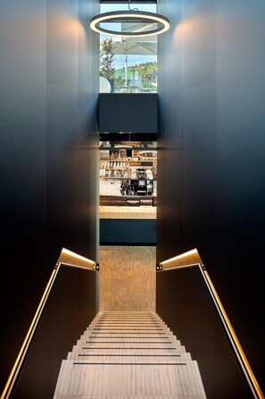 Una escalera moderna que lleva a un área de bar con vistas al exterior.