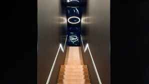 A modern staircase with wooden steps and illuminated handrails, leading to a dark area with circular light fixtures. - Hotel am Remspark (Schwaebisch Gmuend)