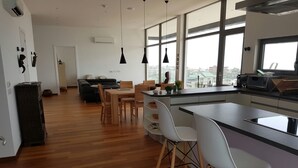 A modern kitchen with a large island, bar stools, and a dining area with a table and chairs. - Suncity Apartments Hotel (Accra)