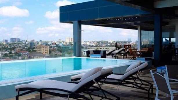 A rooftop pool area with lounge chairs and a view of the cityscape. - Suncity Apartments Hotel (Accra)