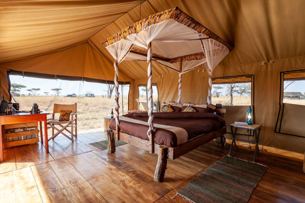 A tent with a bed, a table, and chairs.