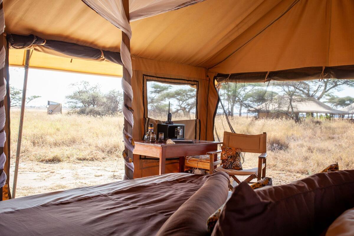 A tent with a bed, a desk with a radio, and a window.