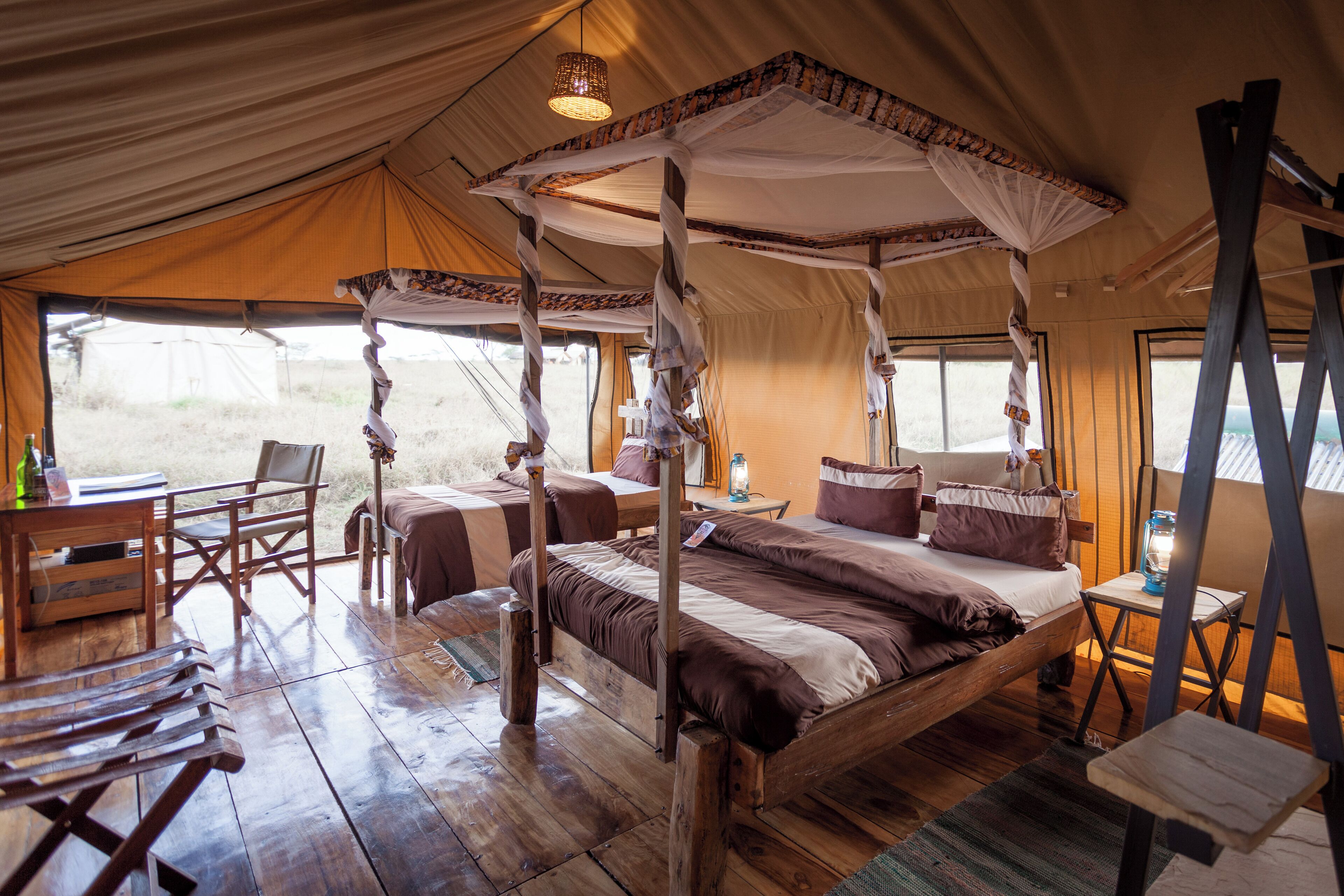 A four-poster bed with a canopy, wooden furniture, and a view of the outdoors.
