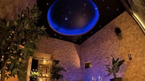 A spa area with a hot tub, a ceiling with a starry design, and a wooden floor. - Magic Apartments (Kraków)