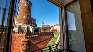 A view from a window overlooking a historic brick tower and a building with a green roof. - Magic Apartments (Kraków)