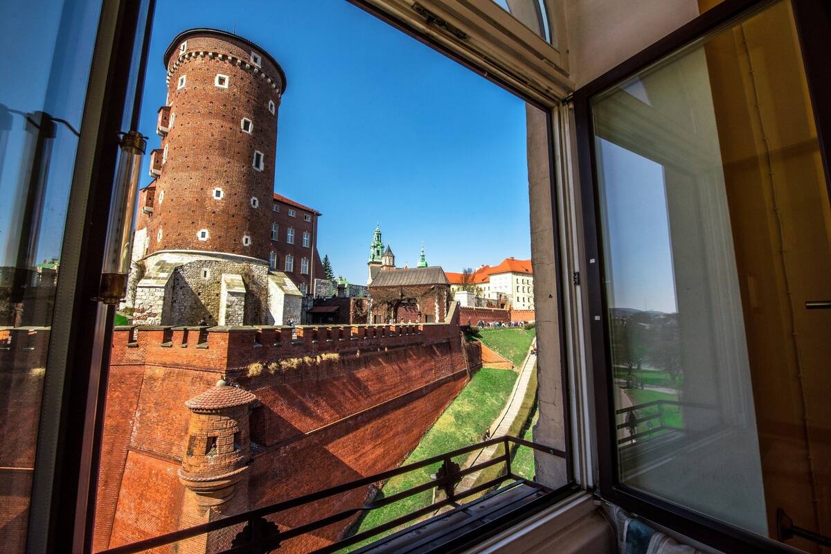 A view from a window overlooking a historic brick tower and a building with a green roof.