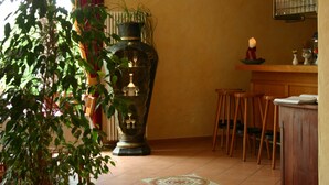 A room with a large vase, wooden stools, a tiled floor, and a window with curtains. - Pension A'MiRo (Rust)