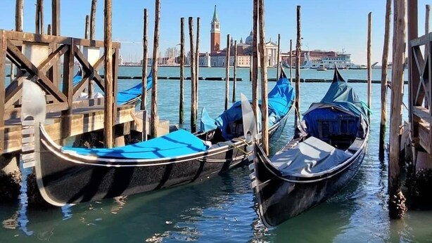 Des gondoles étaient amarrées à un quai, offrant une vue dégagée sur la silhouette de Venise en arrière-plan.